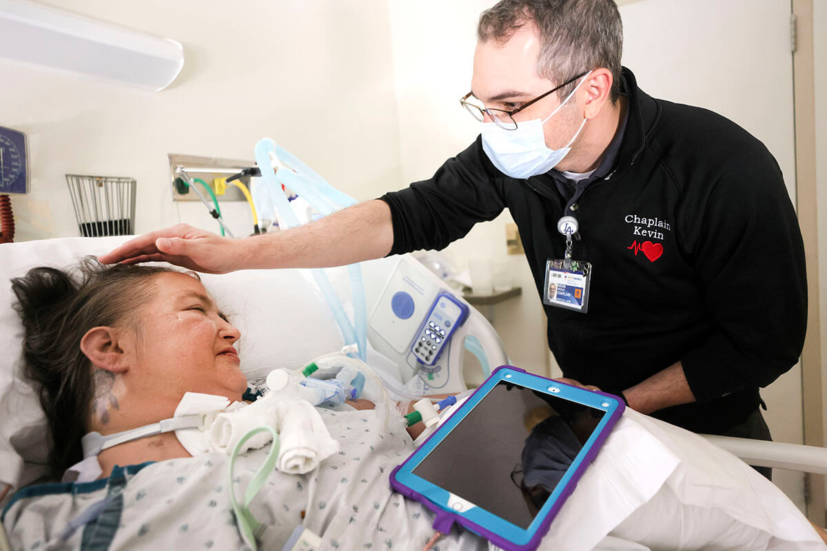 Kevin Deegan, "COVID Chaplain," pictured comforting a patient 